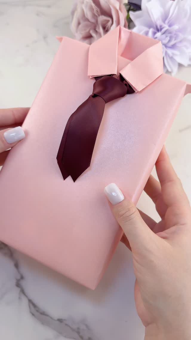 Pink wrapped gift styled as a shirt with a burgundy tie and collar.