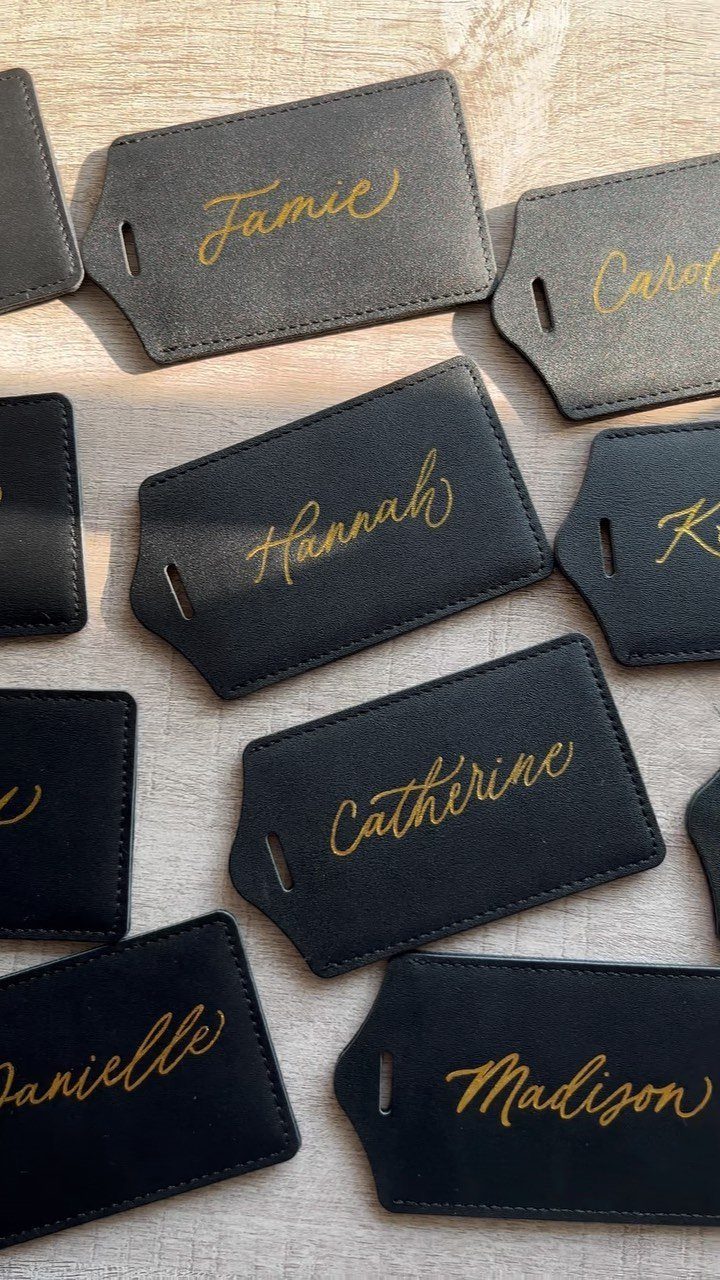 Black leather gift tags with gold calligraphy names on a wooden background