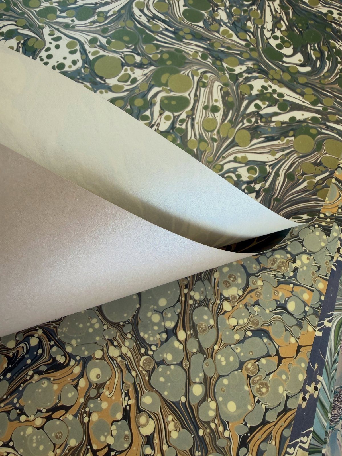 Marbleized wrapping paper with swirling green, blue, and gold patterns curled open.