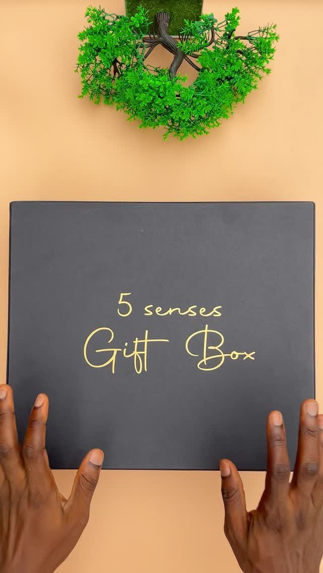 Black gift box with gold text reading 5 senses Gift Box held by hands
