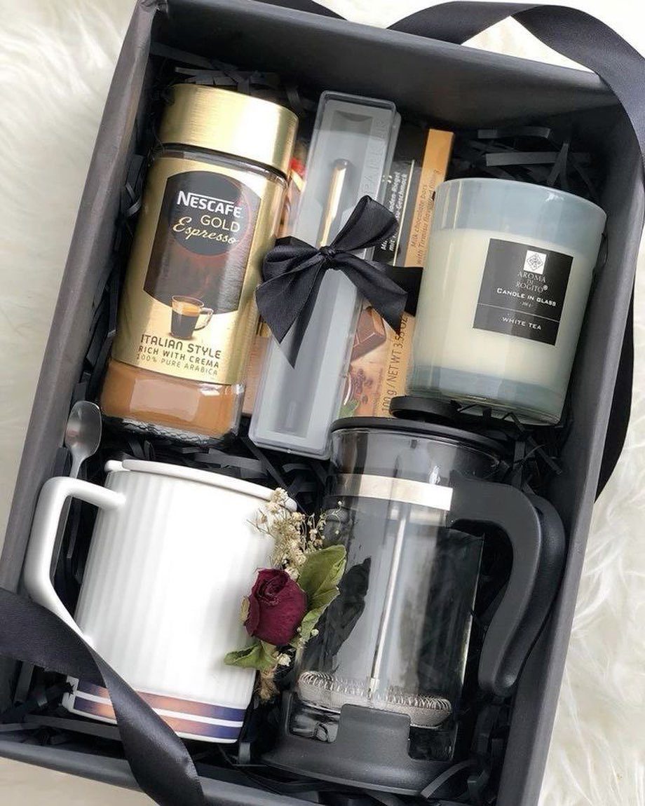 Gift box with espresso coffee, French press, white mug, and scented candle.