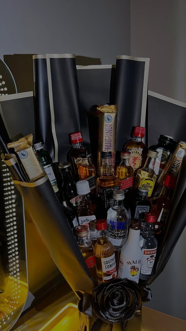 7 Gifts for Dad From Son That Feel Personal and Fun 4 Bouquet of miniature liquor bottles and snacks wrapped in black and gold paper.