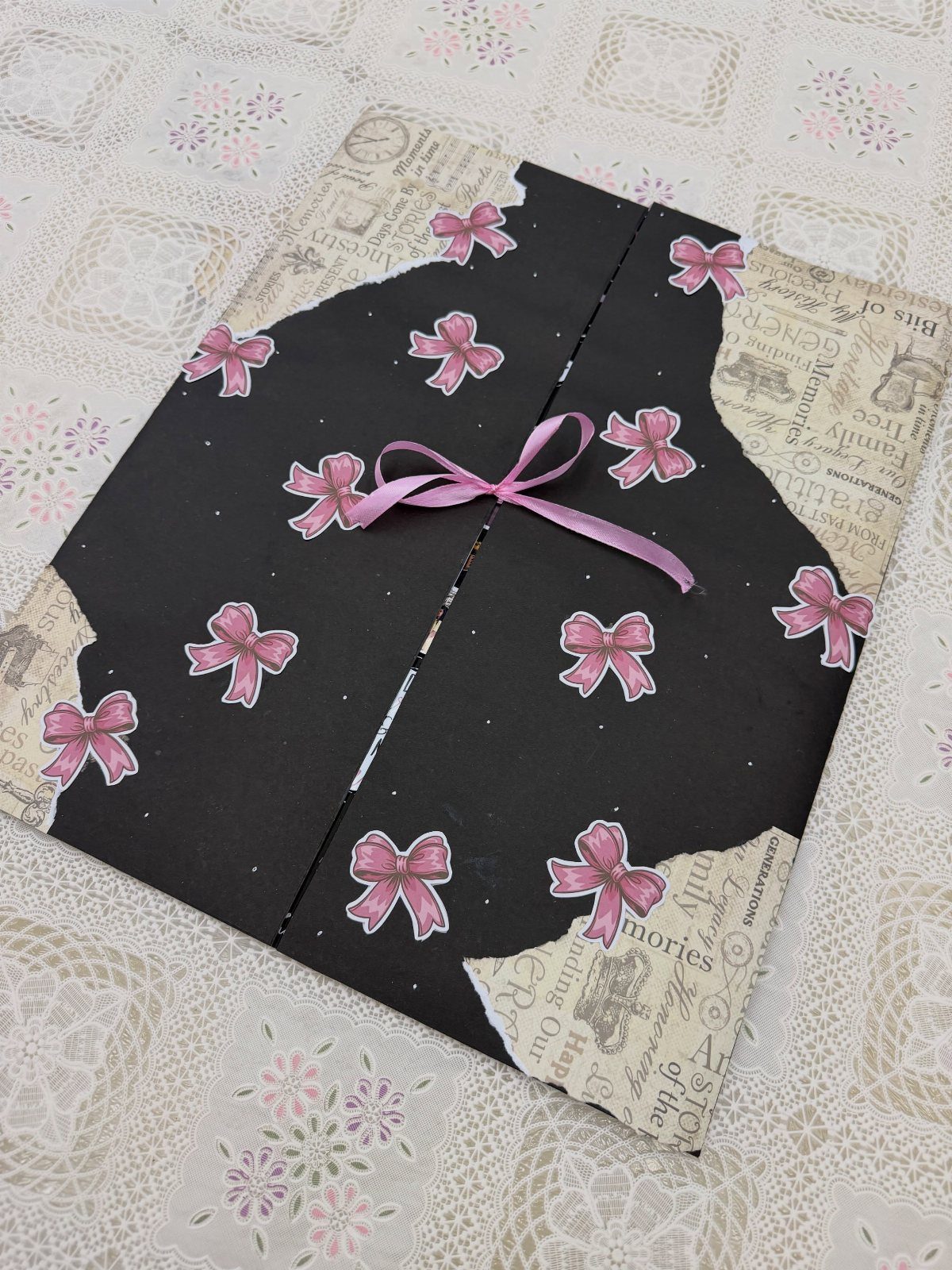 Handmade black card with pink bow stickers and a ribbon on lace tablecloth