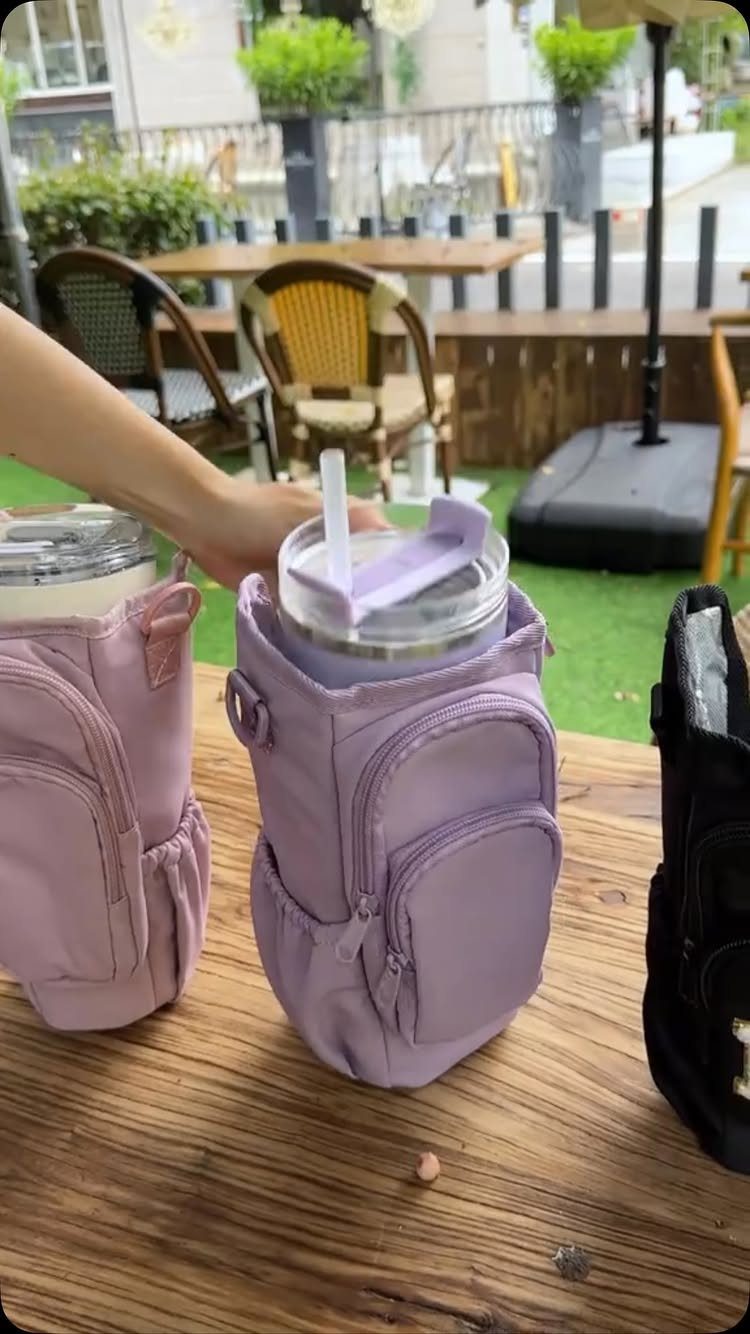 Purple and pink insulated tumbler carriers sitting on a wooden outdoor cafe table
