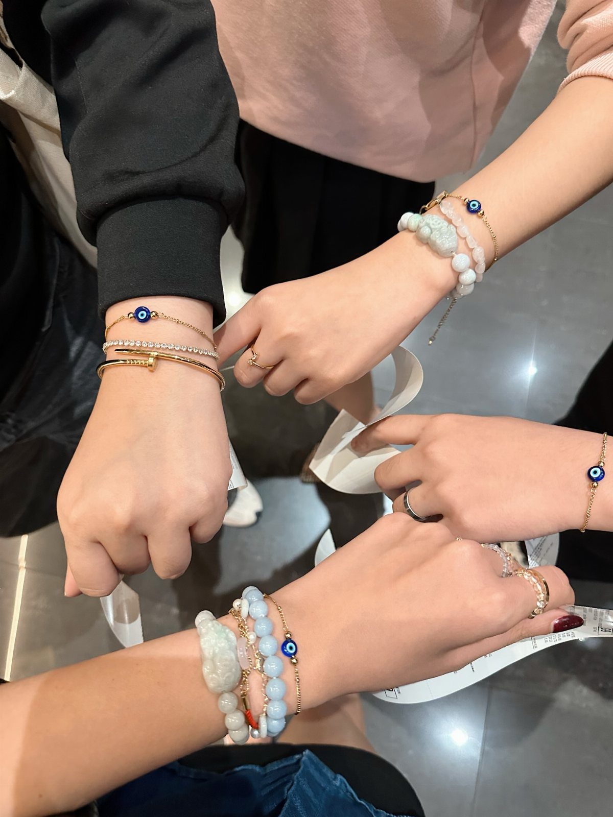 Women's wrists wearing matching gold and beaded evil eye bracelets in a circle