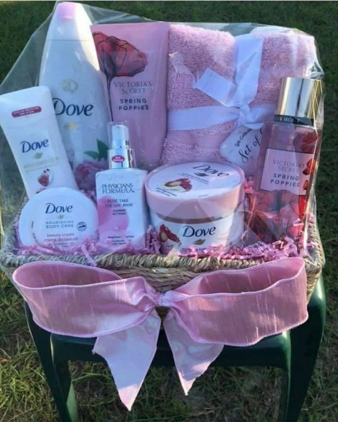 Wicker gift basket filled with pink beauty products and a soft pink towel.