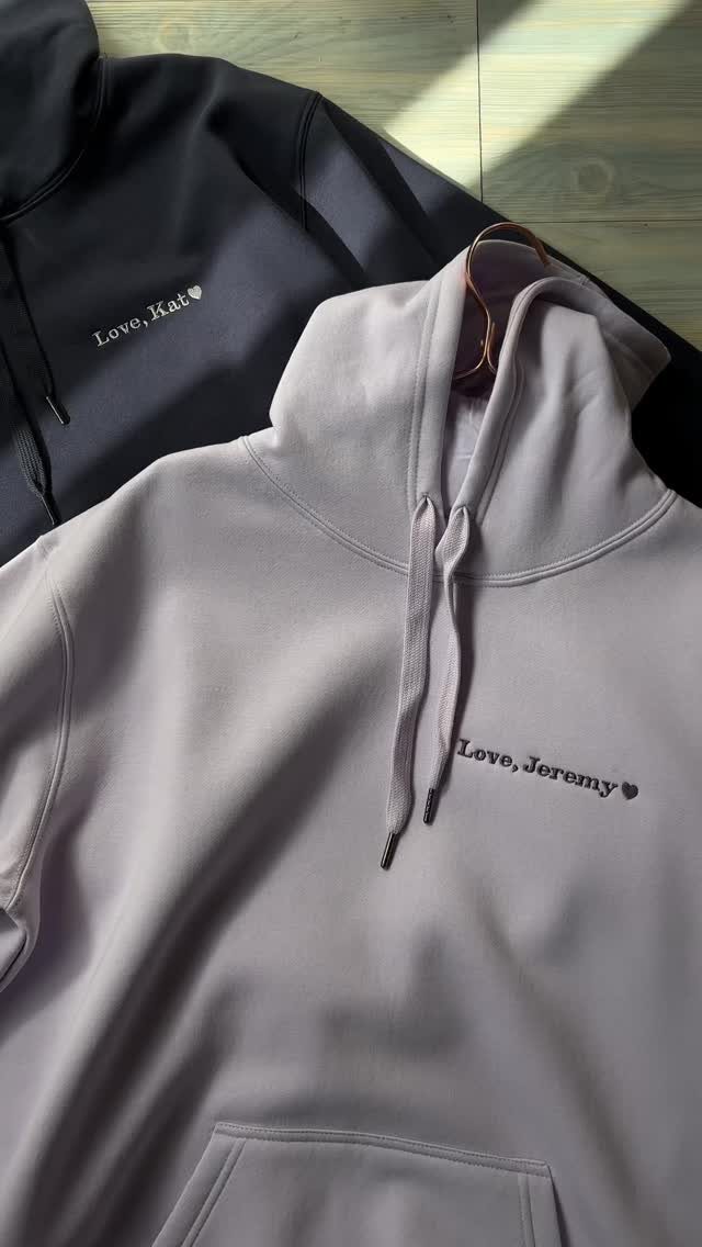 Two embroidered hoodies in navy and lavender with personalized love notes on the chest.