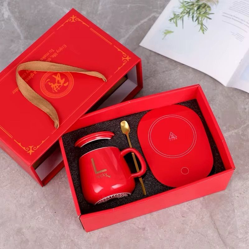 Red gift set with a mug, gold spoon, and warming plate in a box.