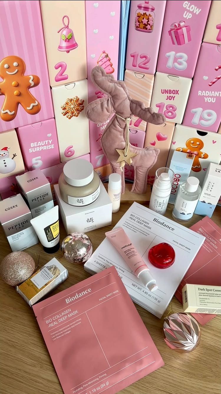Skincare products and pink advent calendar boxes arranged on a wooden table.