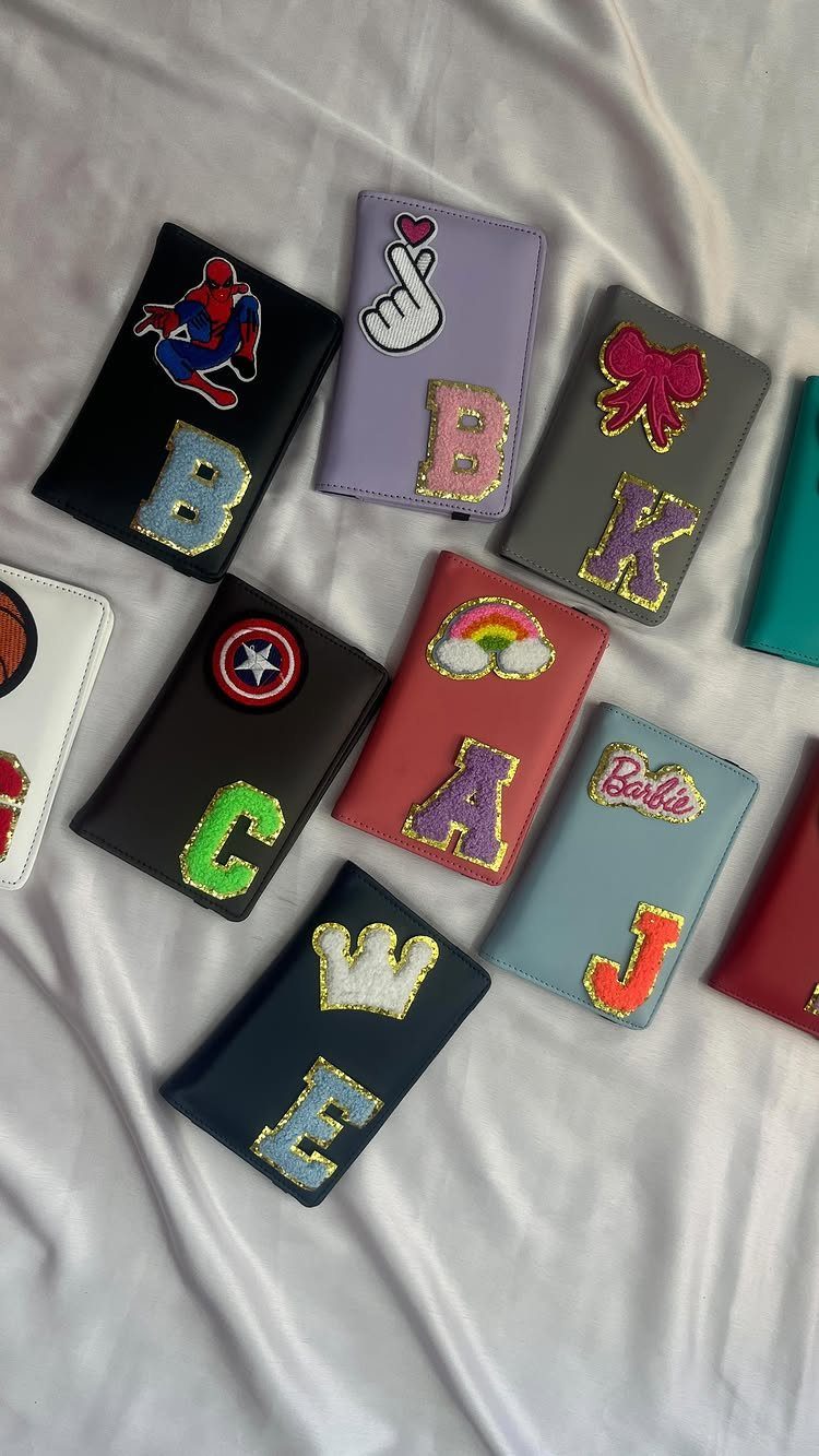 Personalized phone cases with glitter initials and patches on a white fabric background