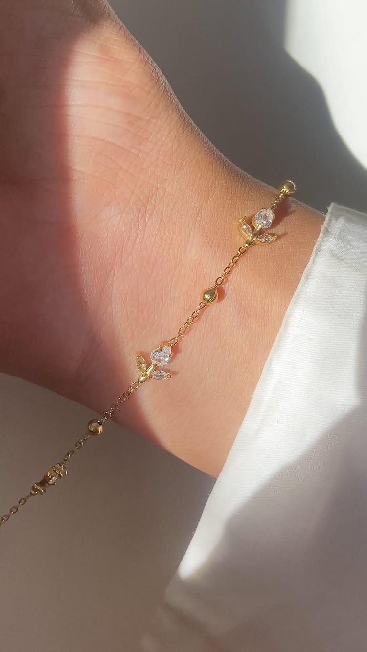 Gold chain bracelet with crystals on a wrist wearing a white sleeve