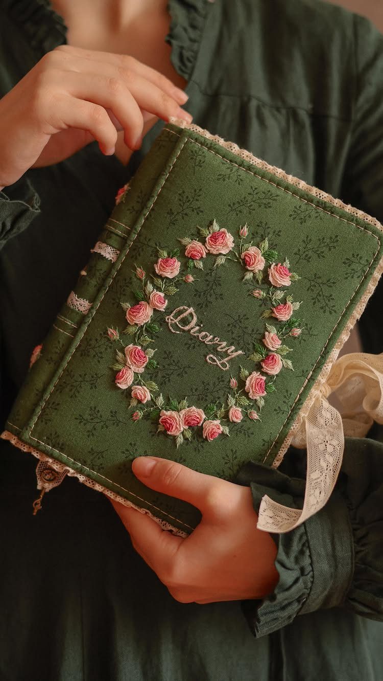 Green fabric diary with pink rose wreath held by person in green dress