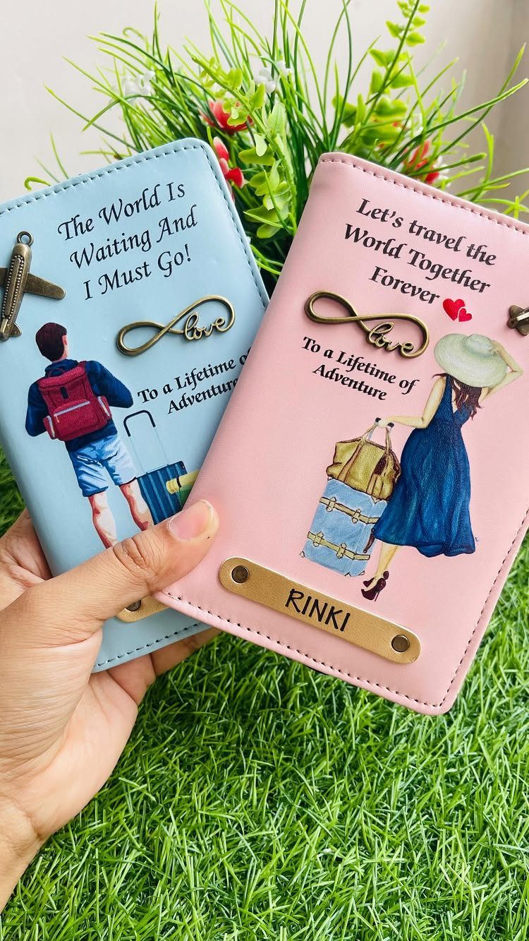 Two personalized faux leather passport holders in blue and pink with travel illustrations.