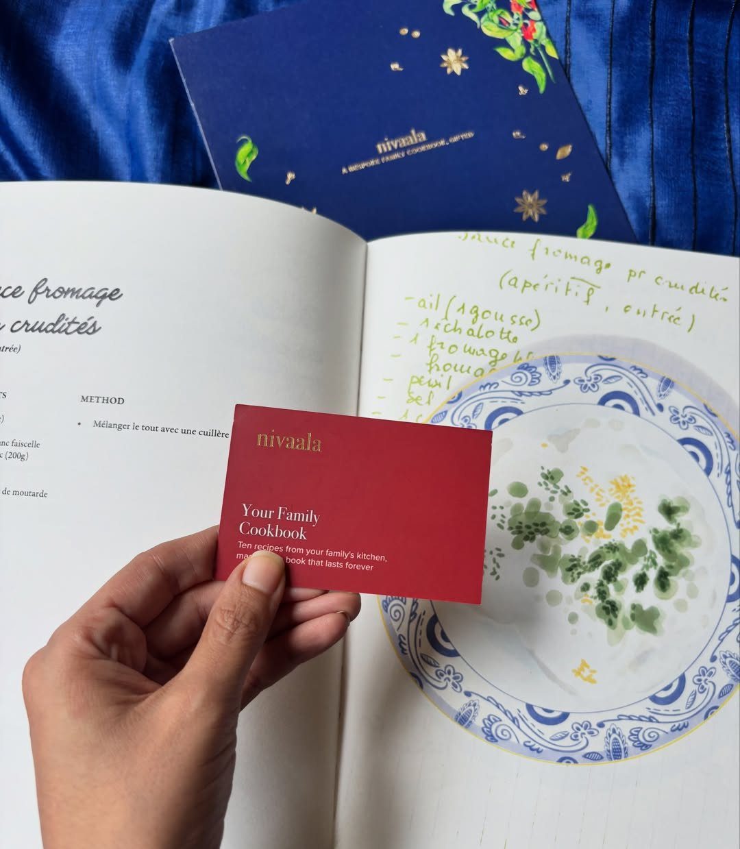 Hand holding a red card over an open personalized family recipe book.