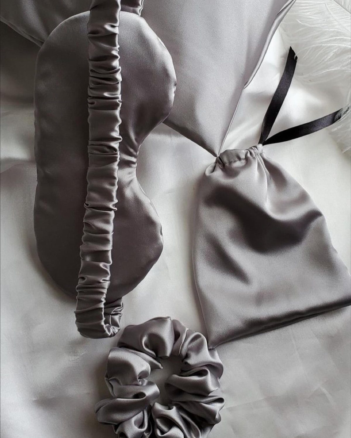 Silver-grey satin sleep set with mask, headband, scrunchie, and pouch on satin fabric.