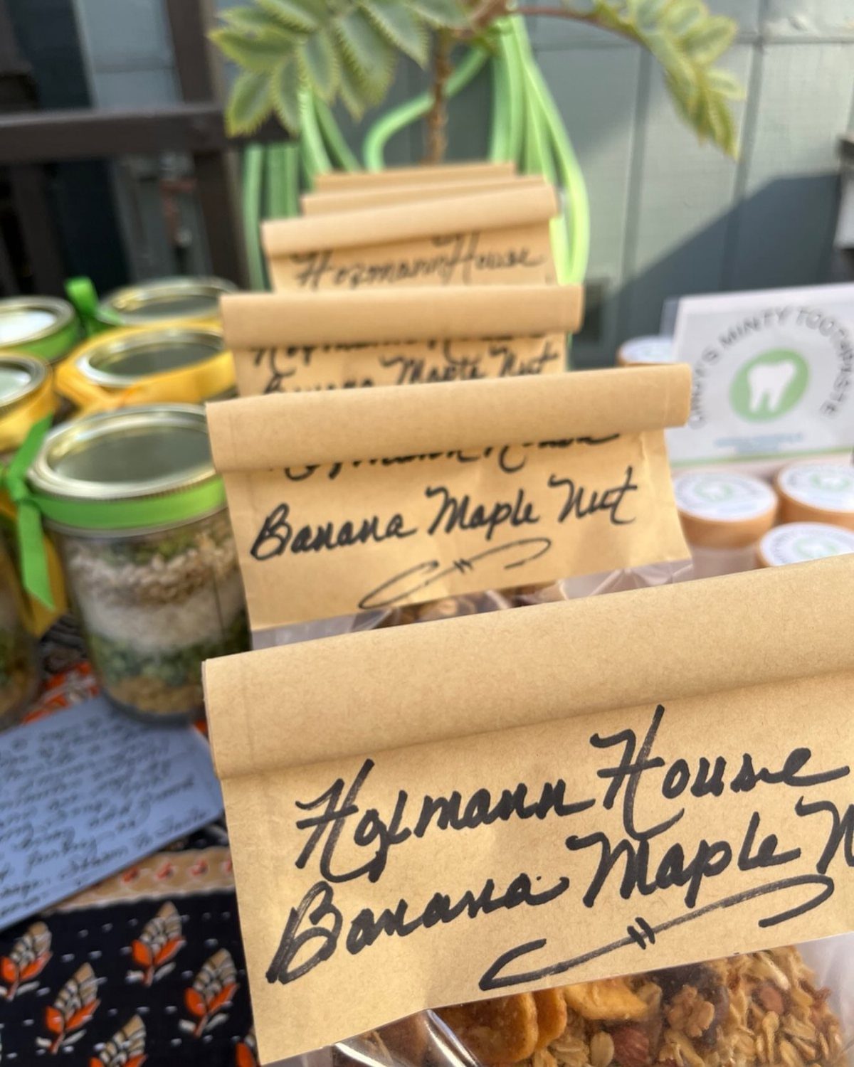 Mason jars and paper bags filled with banana maple nut granola on a table.