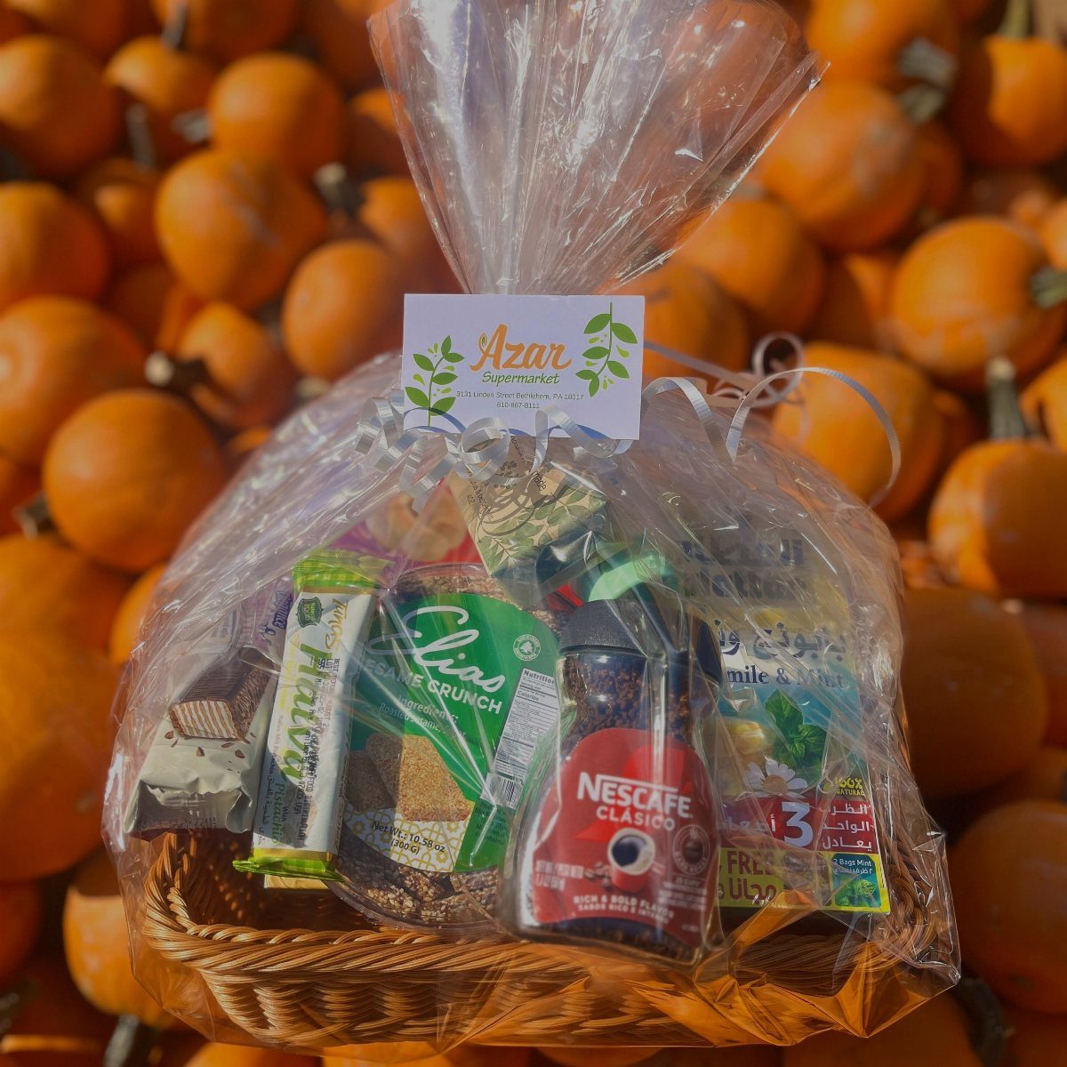 Wicker gift basket filled with packaged snacks and coffee wrapped in clear cellophane.