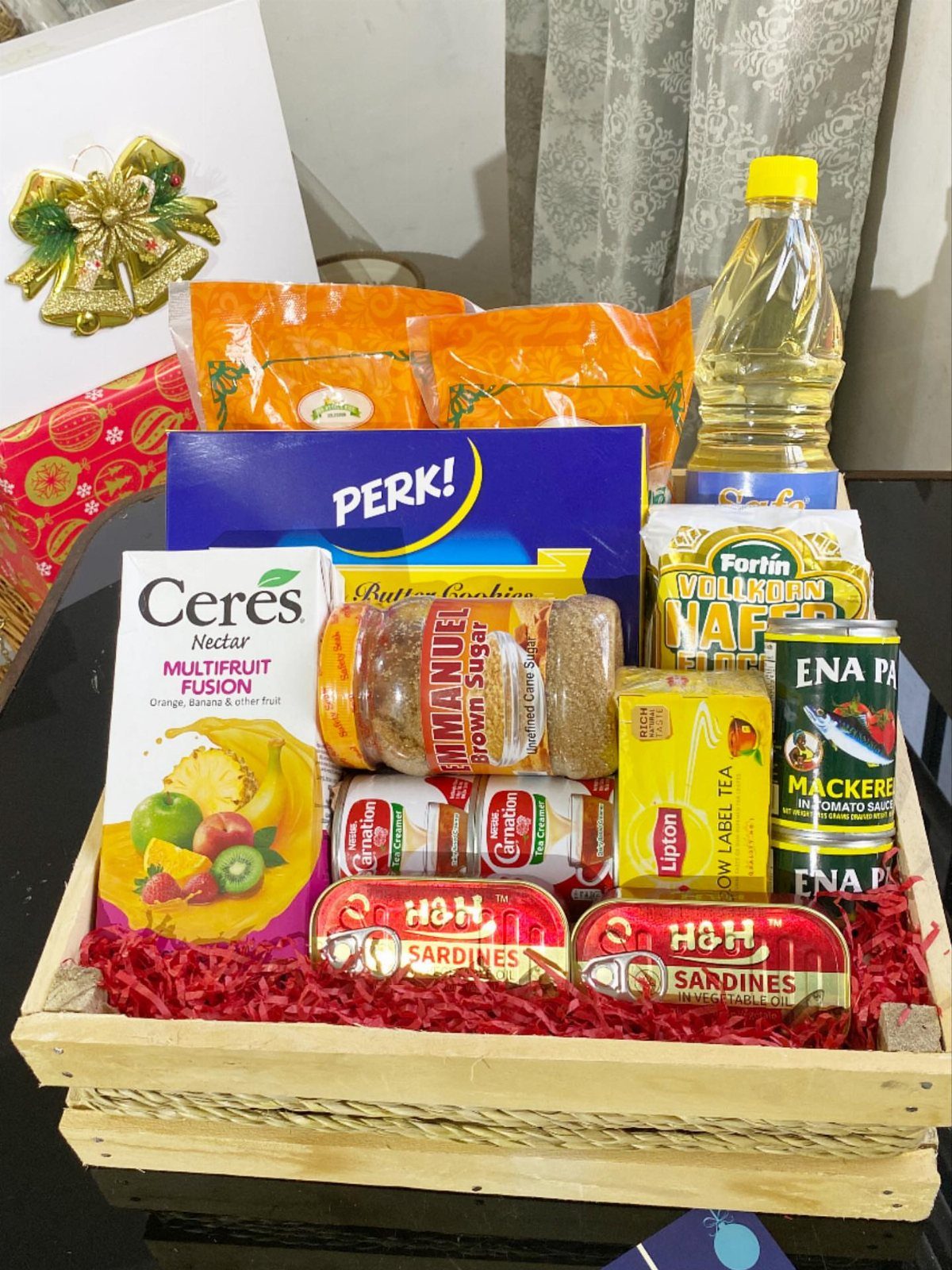 Wooden crate filled with assorted grocery items and canned goods on red paper.