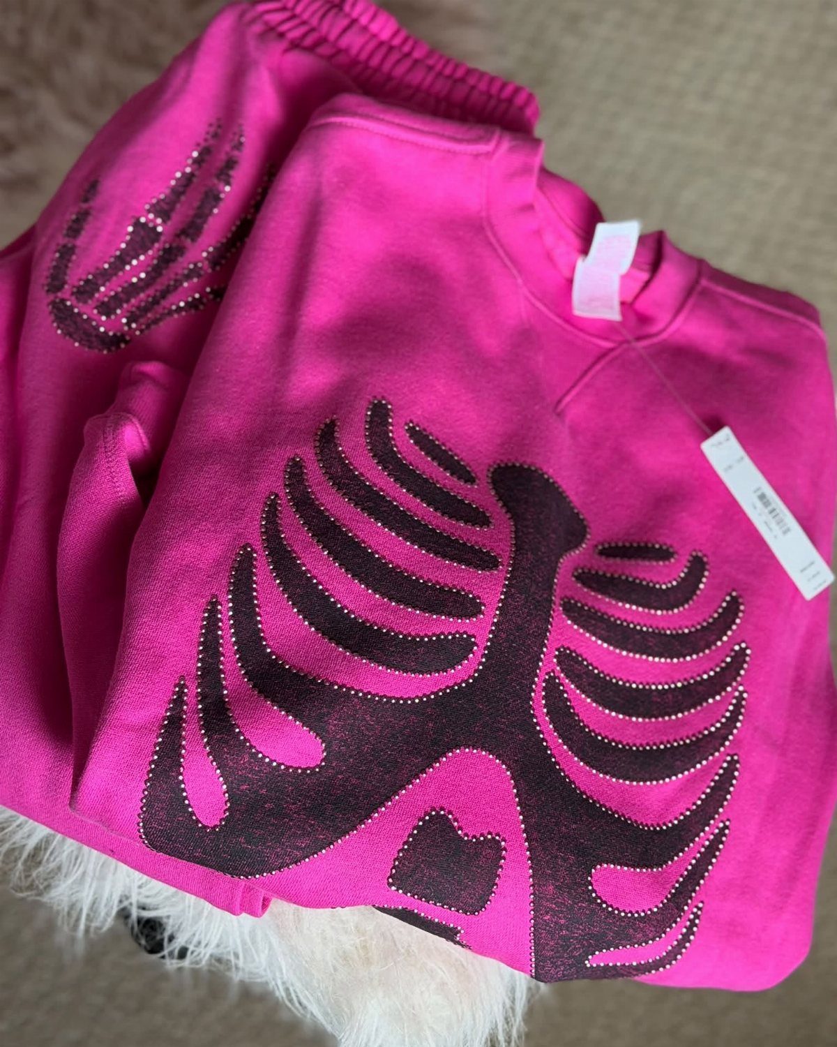 Pink pajama set with a black glittery skeleton ribcage design on a fluffy rug
