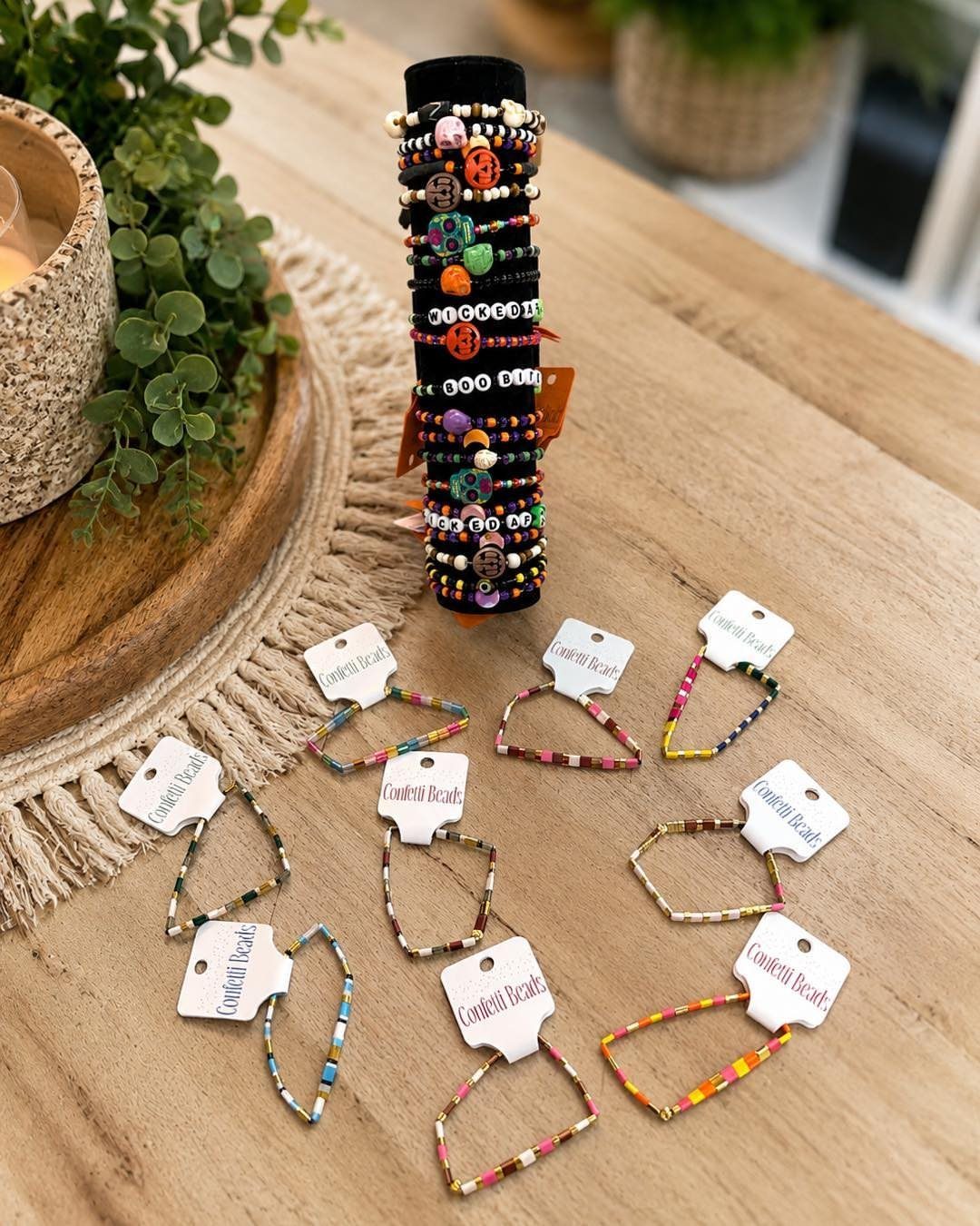 Beaded Halloween bracelets with pumpkin charms on a stand and wooden table