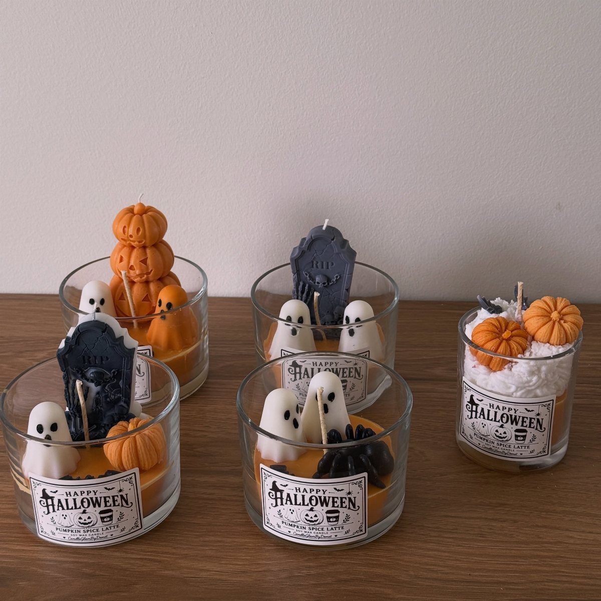 Halloween candles in glass jars featuring wax pumpkins, ghosts, and tombstones.