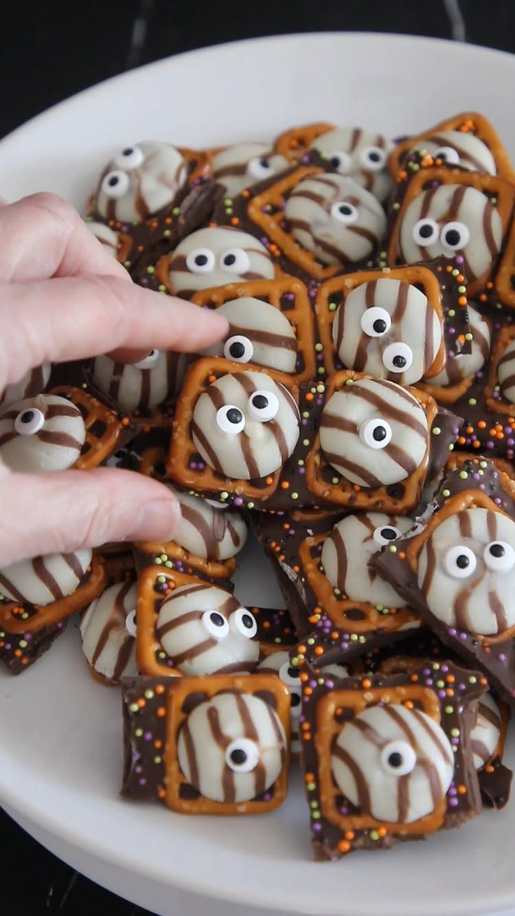 Halloween Food Gifts: 16 Sweet and Spooky Ideas 16 Halloween pretzel treats with chocolate and candy eyes on a white plate