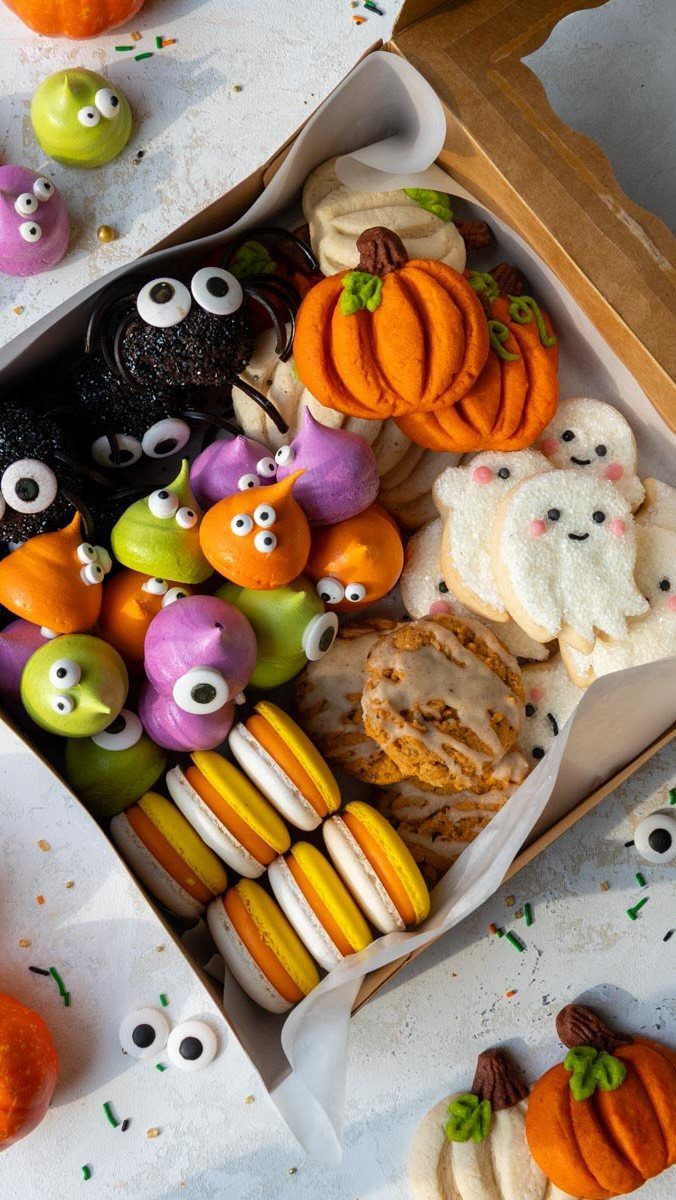 Halloween Food Gifts: 16 Sweet and Spooky Ideas 9 Assorted Halloween treats including pumpkin cookies, ghosts, and macarons in a gift box