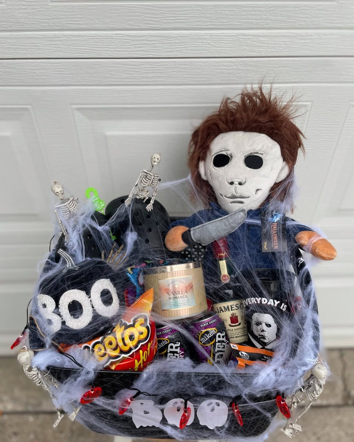 Halloween gift basket with Michael Myers doll, snacks, and white spiderweb decorations.