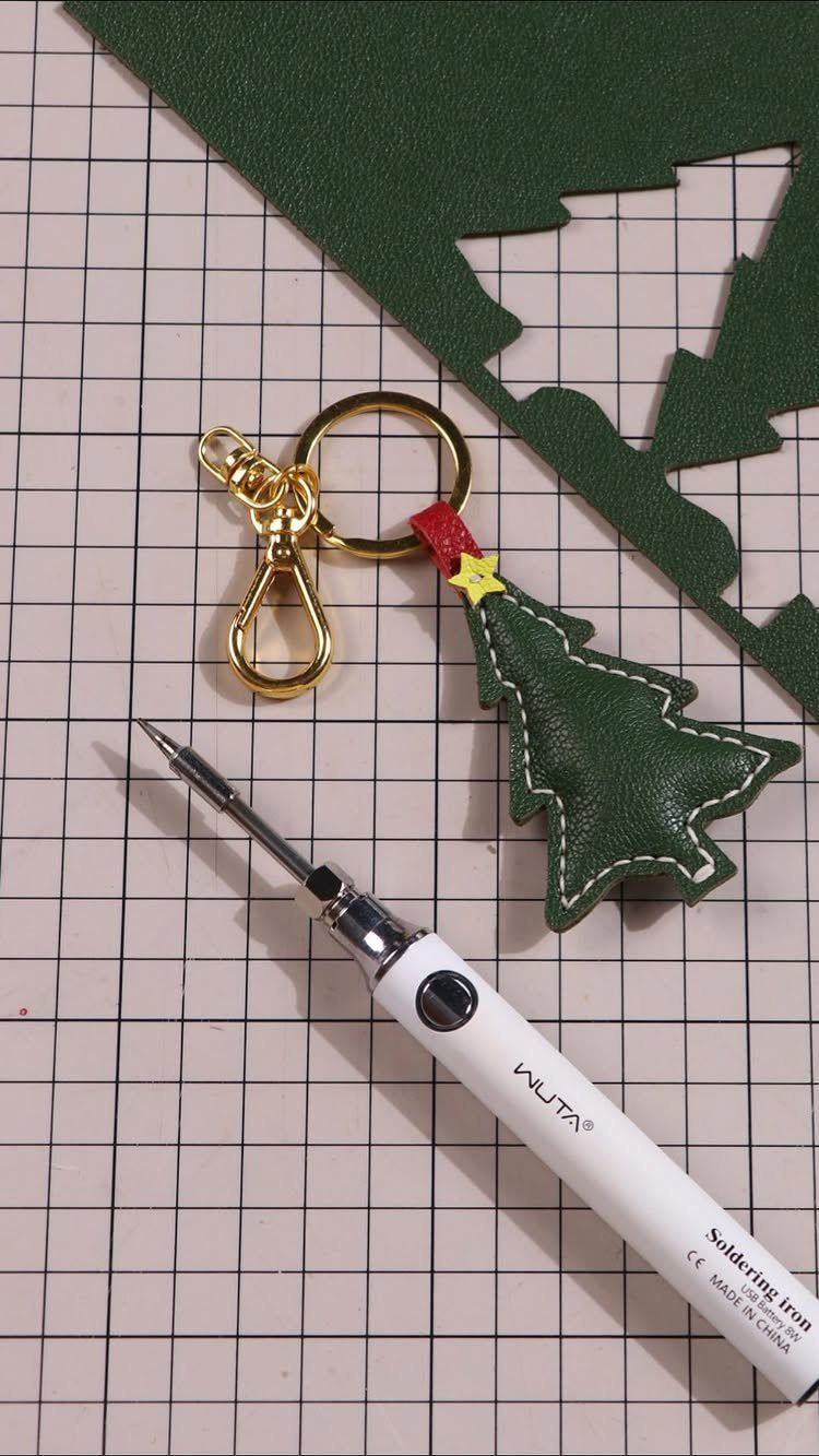 5 Homemade Christmas Gifts for Dad You Can Make 3 Green leather Christmas tree keychain with a soldering iron on a grid mat.