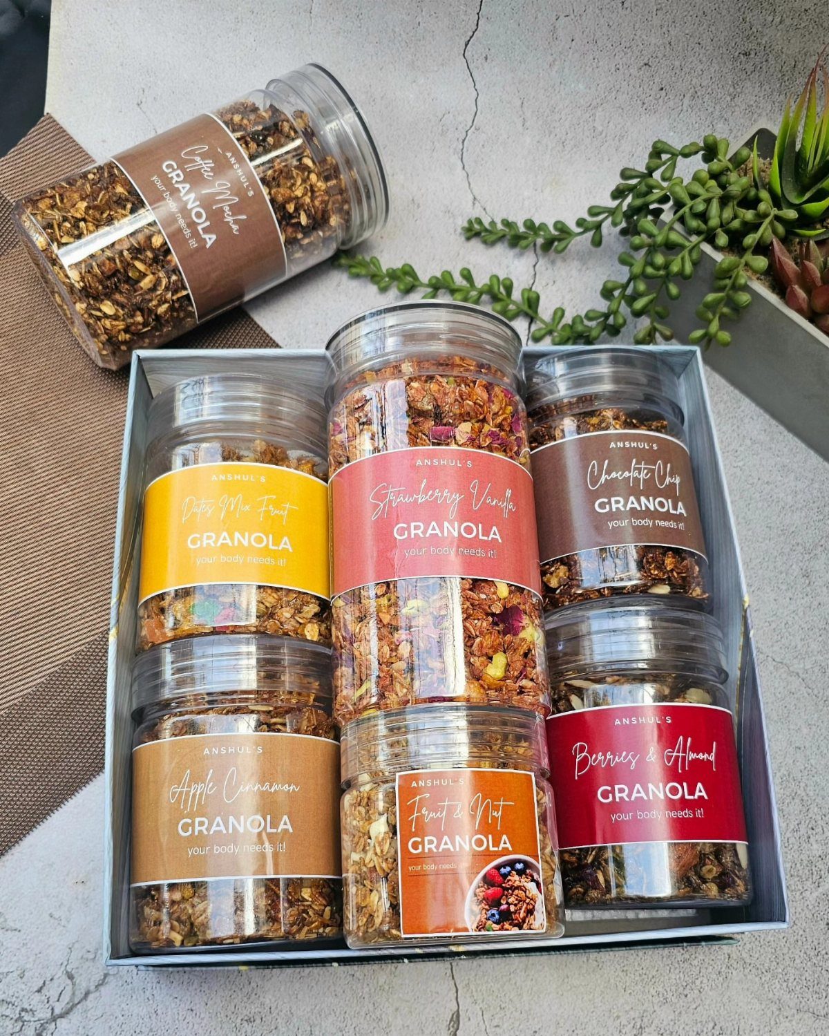 13 Homemade Gift Ideas for Coworkers They'll Use 5 Glass jars filled with granola and colorful labels arranged in a gift box.