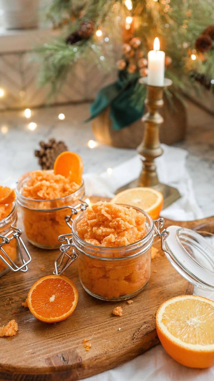 Orange granulated scrub in glass jars on a wooden board with citrus slices