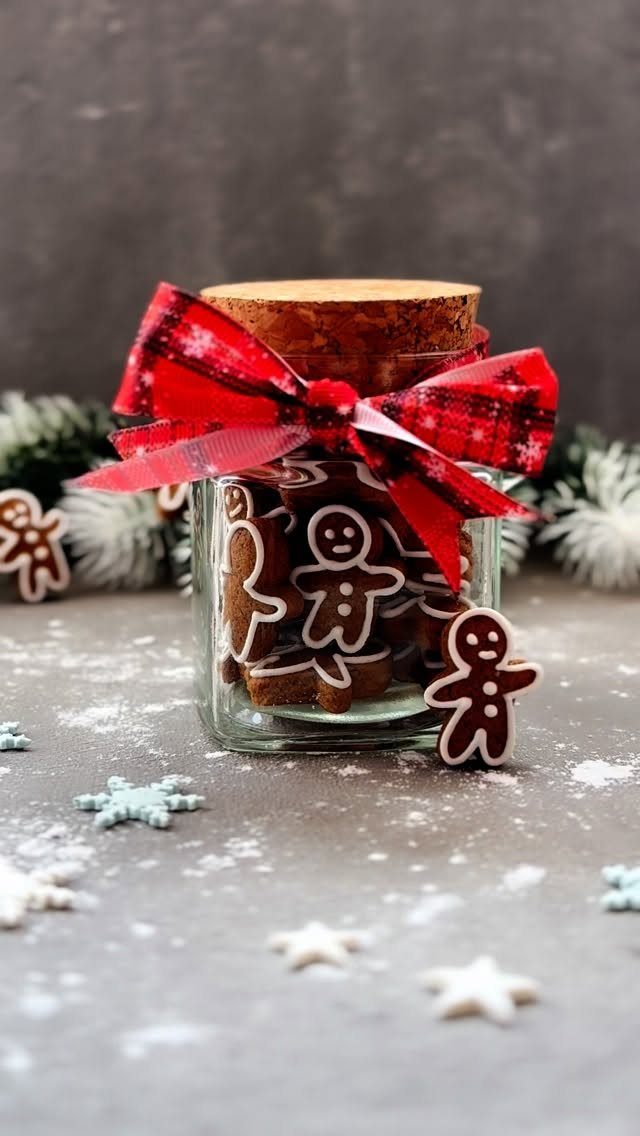 Glass jar filled with gingerbread man cookies tied with a red plaid ribbon.
