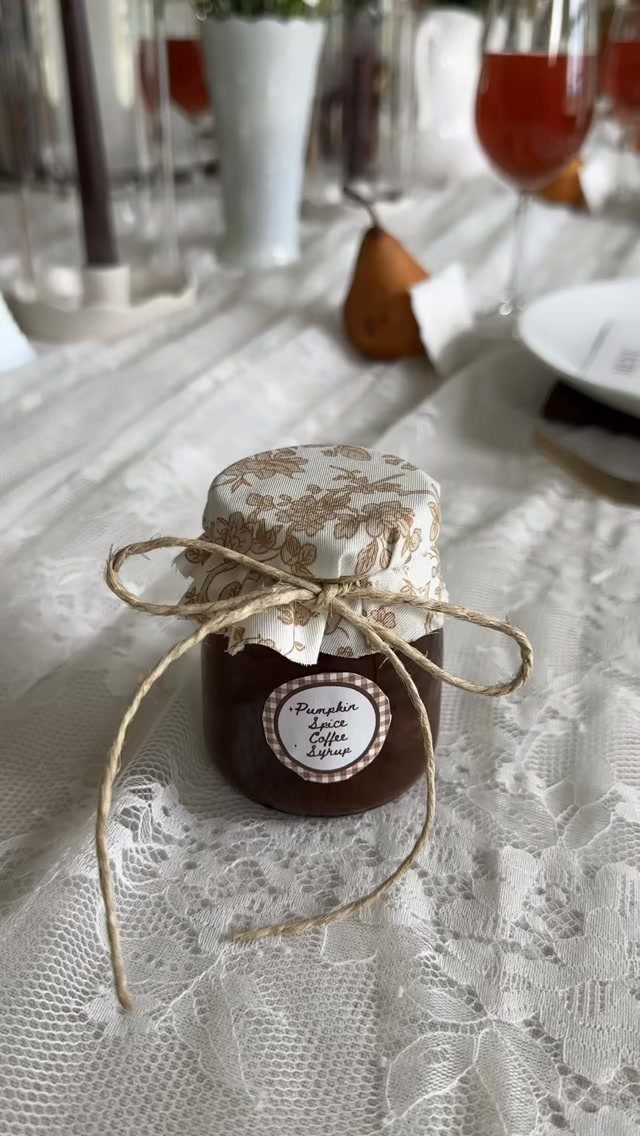 Small glass jar of pumpkin spice coffee syrup with floral lid and twine.