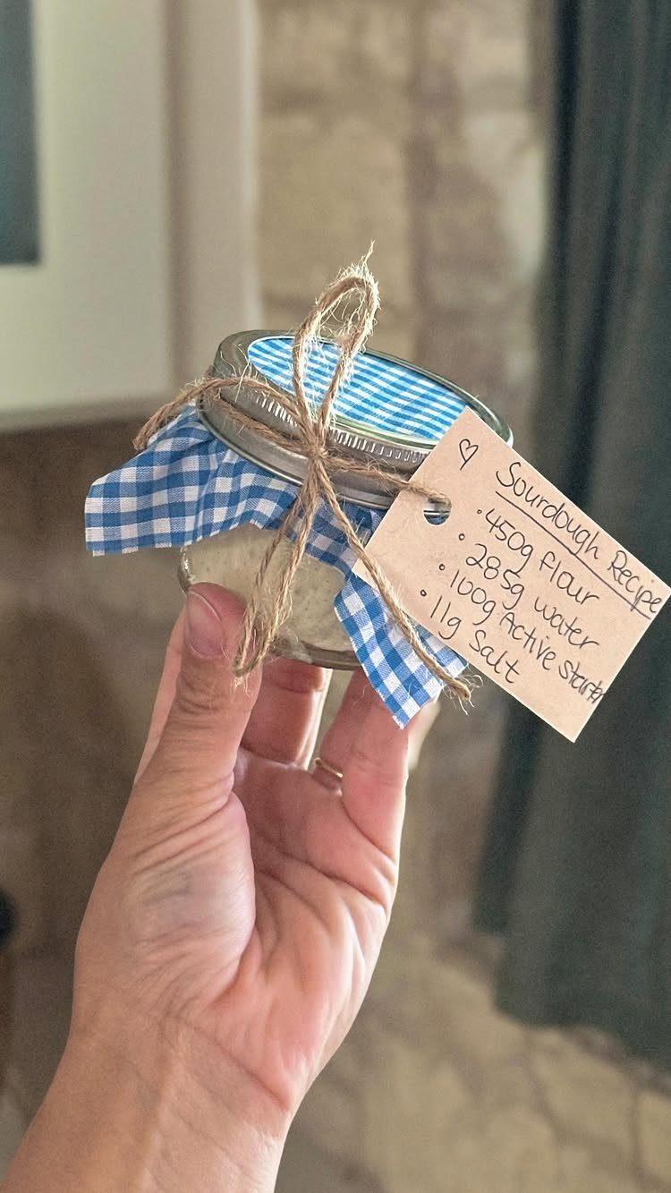 Glass jar with sourdough starter, blue checkered lid, and handwritten recipe tag.