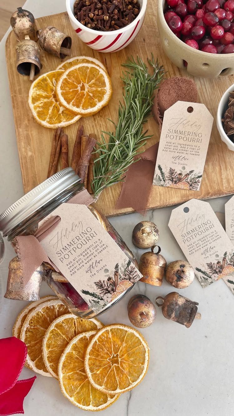 Glass jar of simmering potpourri surrounded by dried oranges, cinnamon, and cranberries.