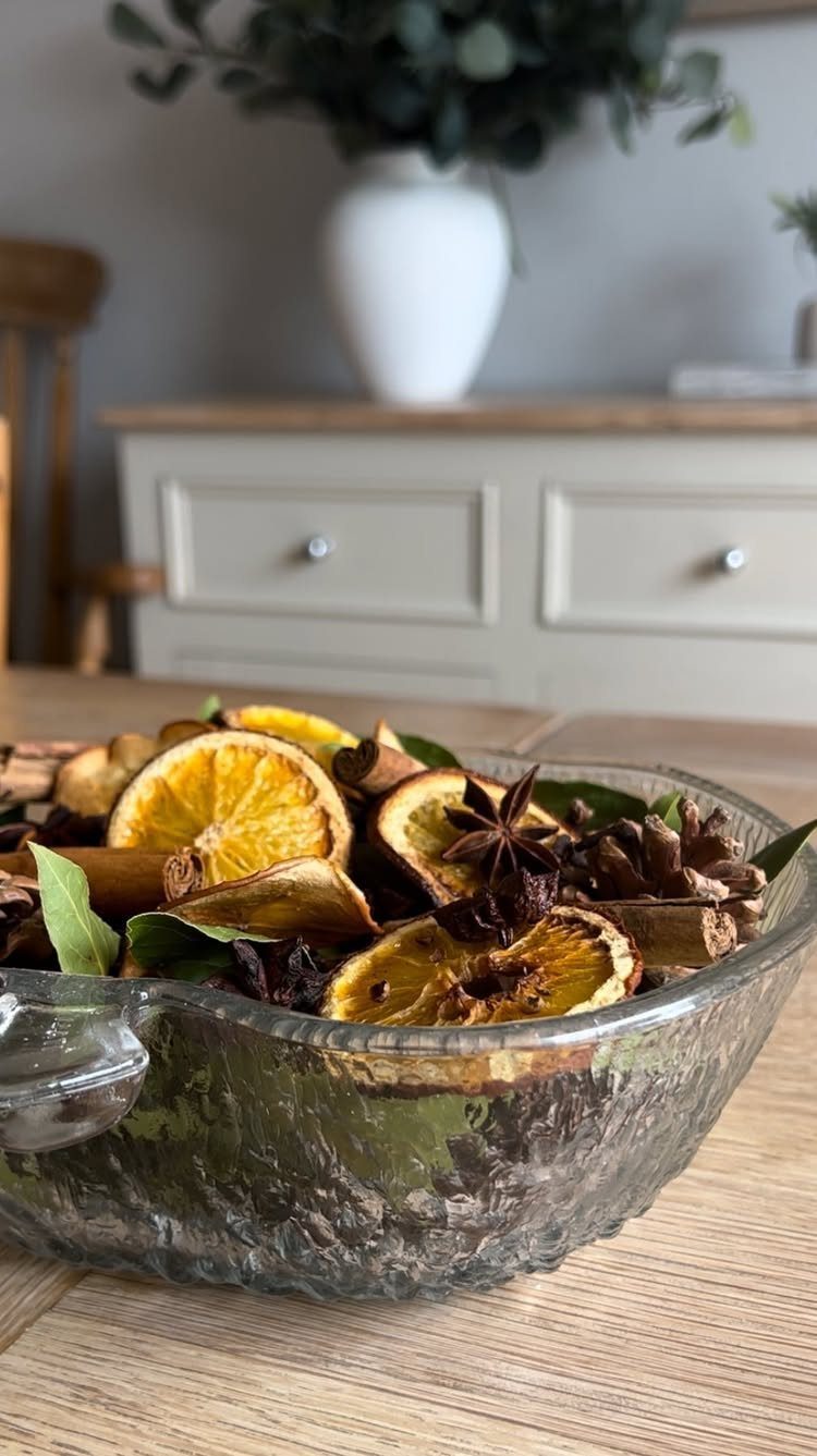 Dried orange slices, cinnamon sticks, and star anise in a glass bowl.