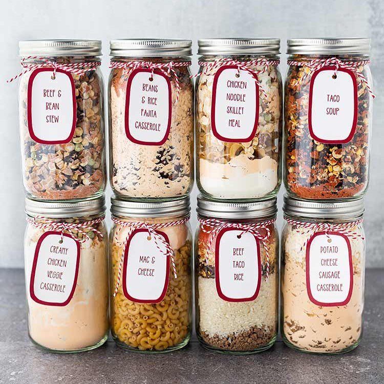Eight mason jars filled with layered dry ingredients for various homemade meal recipes.