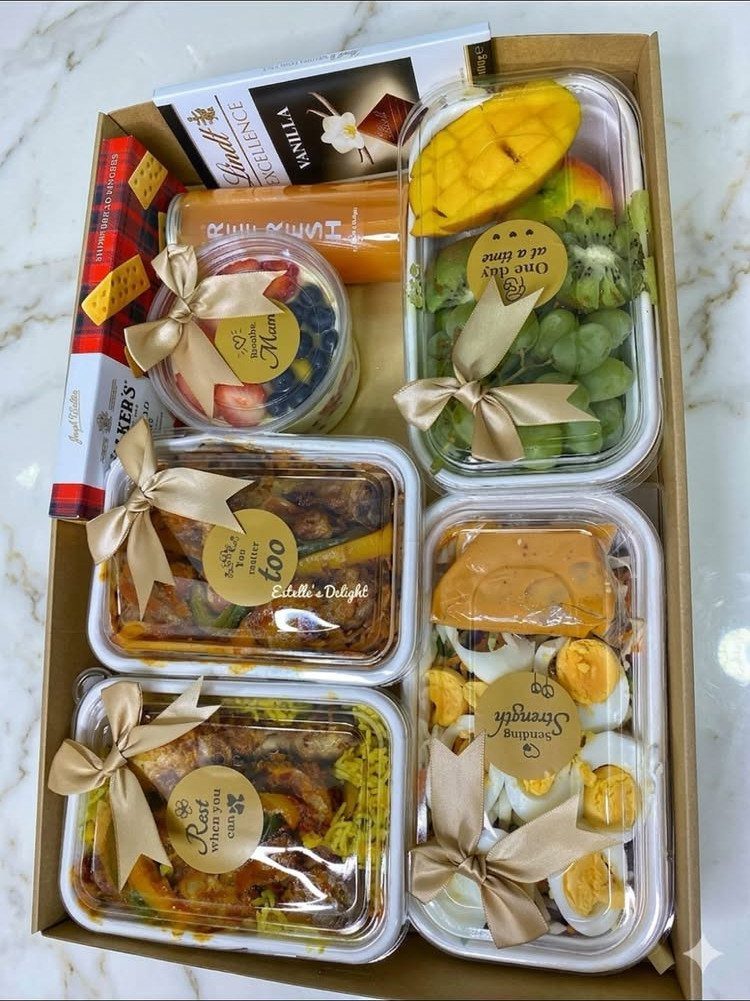5 Housewarming Gift Ideas for Someone Who Has Everything 5 Prepared meals in plastic containers with gold ribbons inside a cardboard gift box.