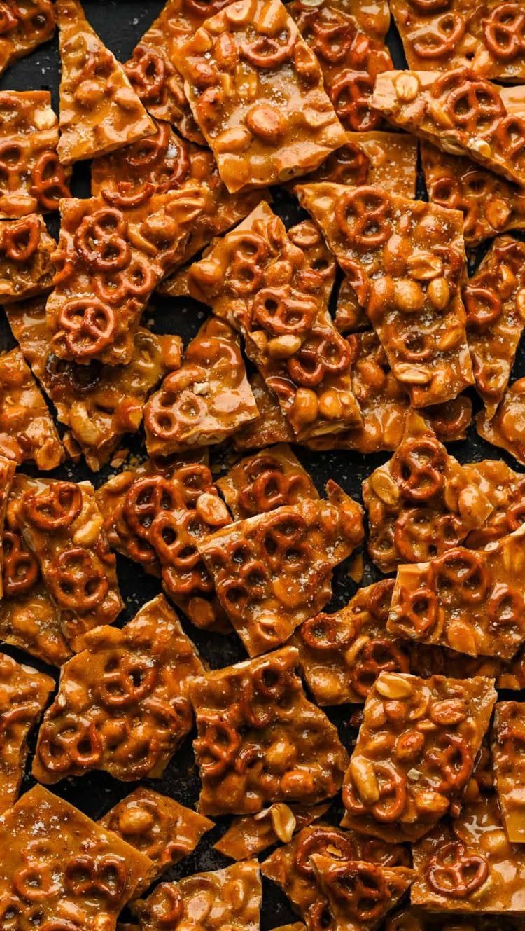 Peanut butter and pretzel brittle pieces scattered on a dark background.