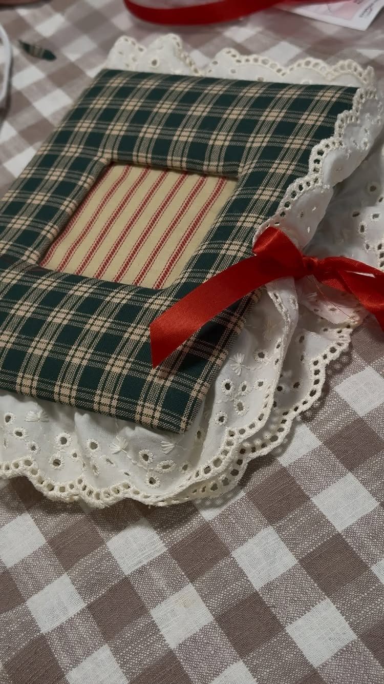 Handmade plaid fabric picture frame with a red bow on a lace doily.