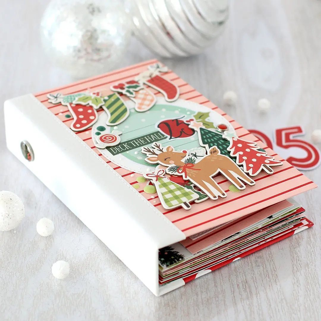 Handmade Christmas scrapbook with reindeer and stocking decorations on a striped cover.