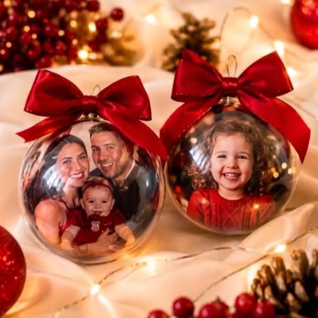 Two glass Christmas ornaments with family photos inside and red satin bows.