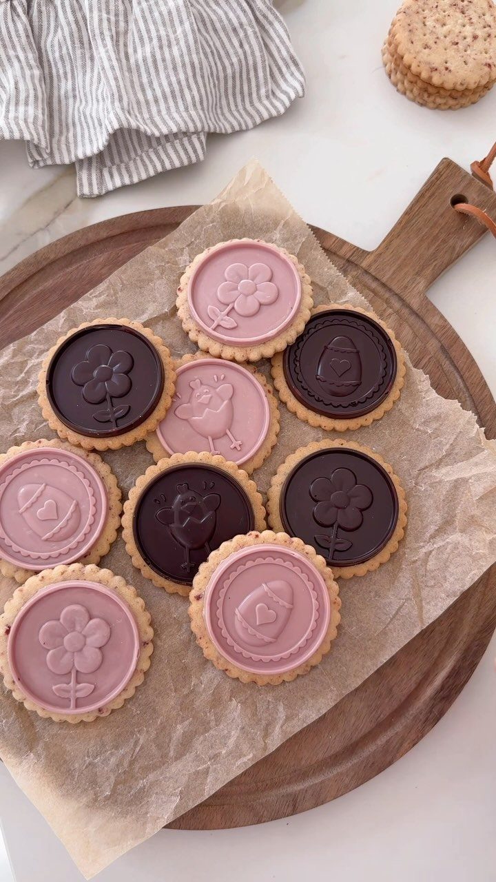 Round Easter cookies with pink and brown embossed chocolate toppings on a wooden board