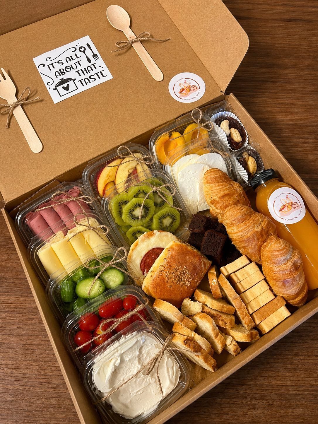 Breakfast gift box with croissants, fresh fruit, cheese, meats, and orange juice.