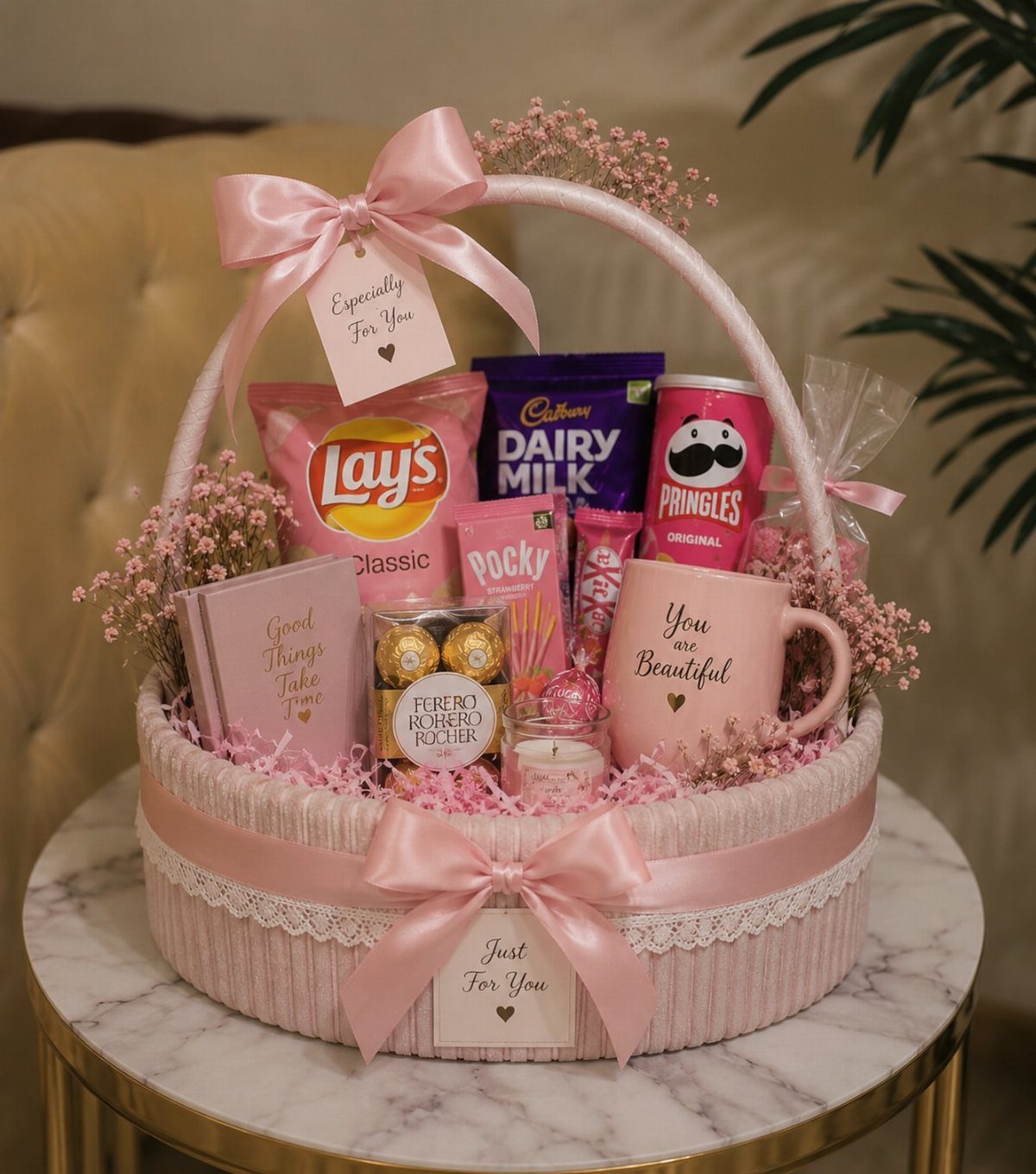 Pink gift basket filled with assorted snacks, chocolates, and a decorative pink mug.