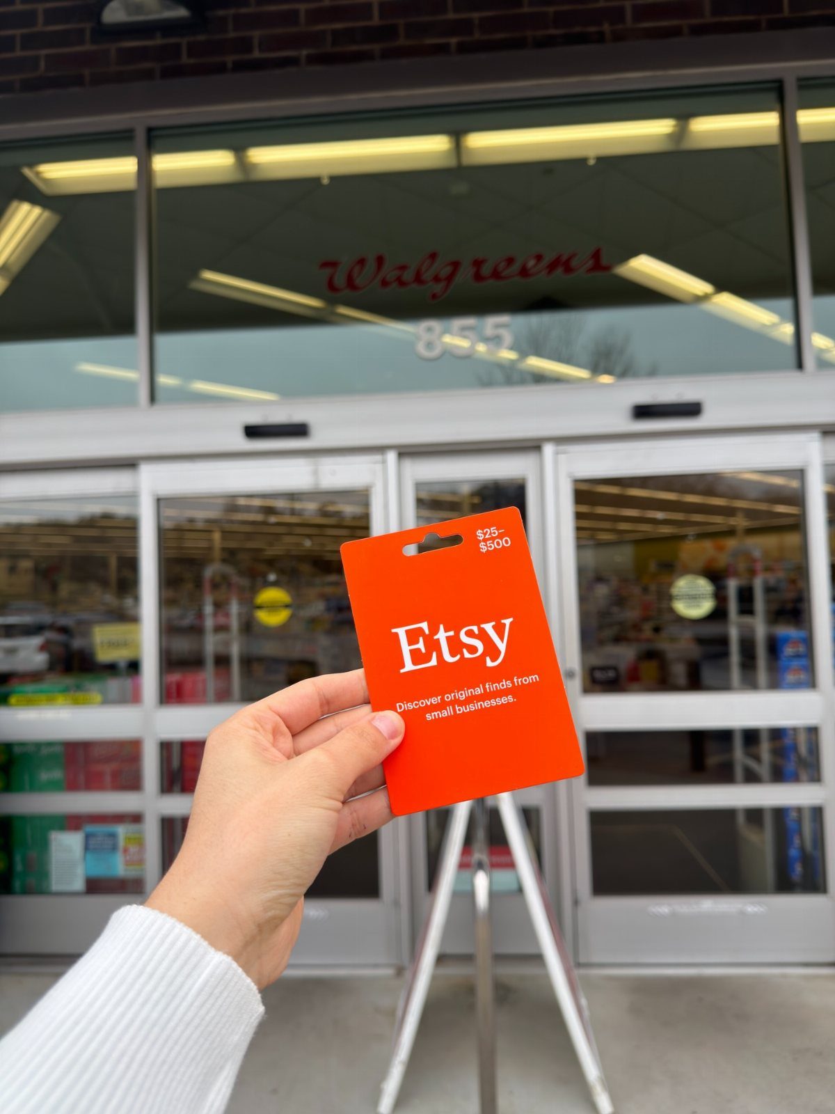 11 Mother in Law Birthday Gift Ideas She Will Actually Use 11 Hand holding an orange Etsy gift card in front of a Walgreens store