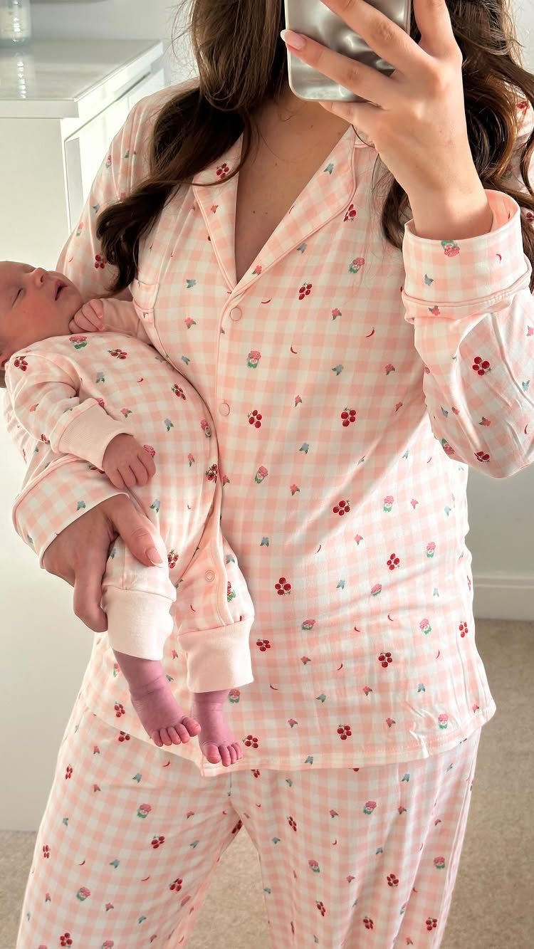 Woman and newborn baby wearing matching pink and white gingham floral pajamas.