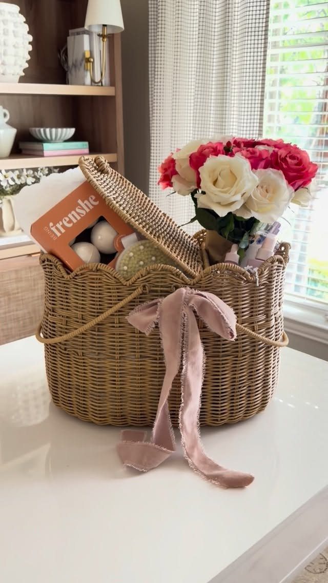 Woven wicker gift basket with pink ribbon, roses, and self-care products on white table.