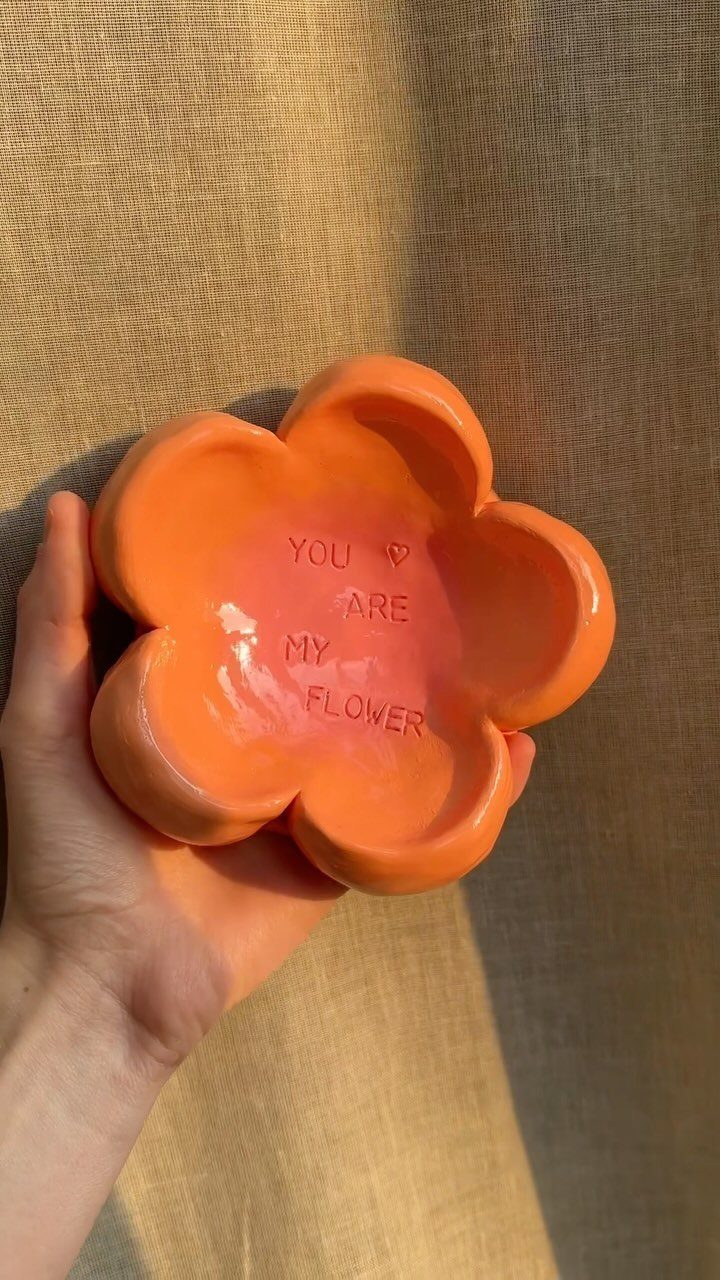 18 Mothers Day Gifts to Make: Easy Handmade Ideas for Mom 17 Orange flower-shaped ceramic dish with stamped text held in a person's hand.