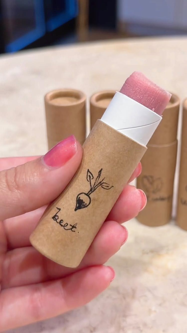 18 Mothers Day Gifts to Make: Easy Handmade Ideas for Mom 18 Pink lip balm in a cardboard tube held by a hand with pink nails.